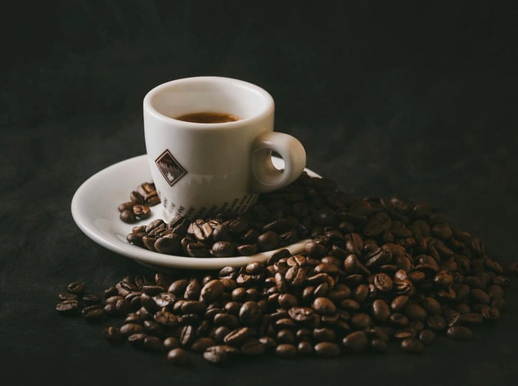 Tazzina Caffé Milani con accanto chicchi di caffè in grani